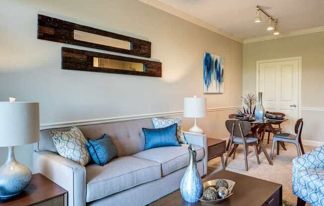 A living room with a grey couch, a coffee table, and a dining table.