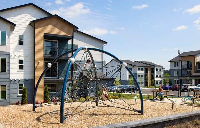 a playground with a climbing frame in front of a row of apartment buildings