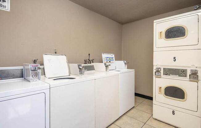 A laundry room with washing machines and dryers.