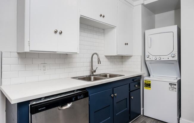 a kitchen with white cabinets and blue counters and a white washer and dryer