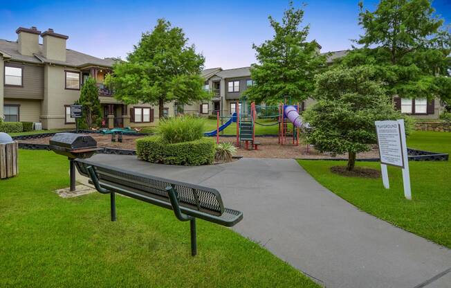 a park with a playground and benches and buildings in the background