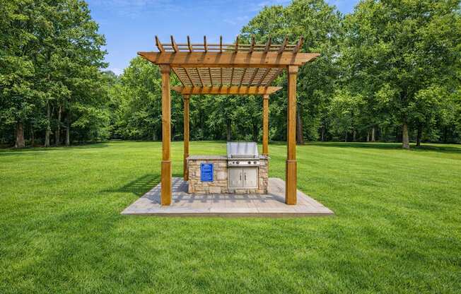 A wooden structure with a blue sign on it is in the middle of a grassy field.