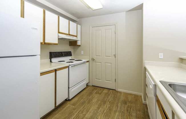 A kitchen with white appliances and wooden floors.