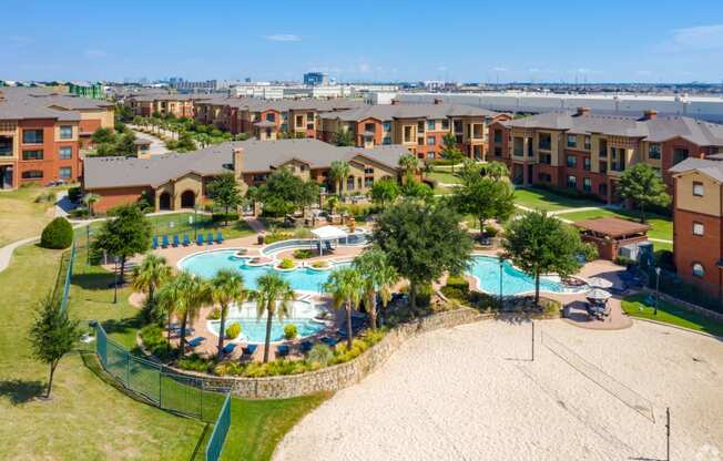Resort-Style Pool and Volleyball at Bella Madera Lewisville with tons of greenery and palm trees