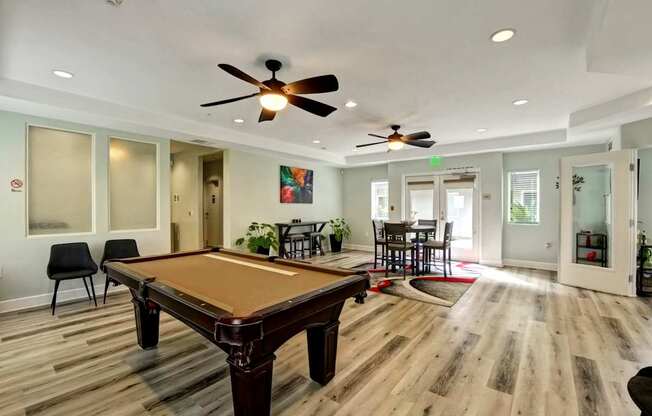 A room with a pool table and chairs.
