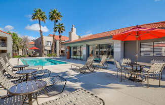 A poolside area with chairs and tables.