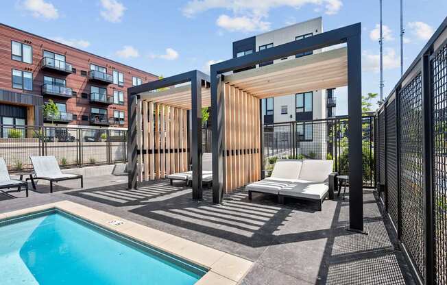 A modern outdoor pool area with a wooden structure and lounge chairs.