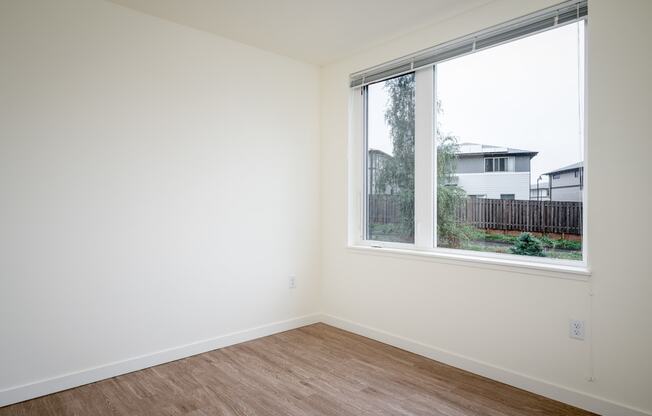 an empty room with a large window and wooden floors