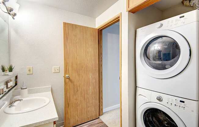 A white washing machine sits in a laundry room next to a sink.