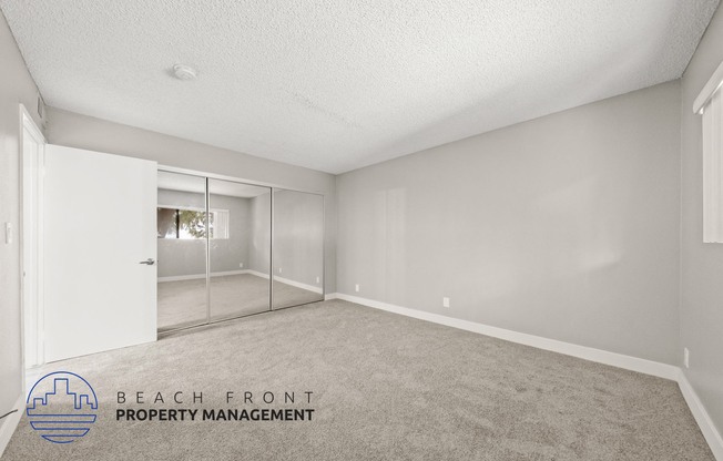 the living room of an apartment with carpet and a mirrored closet