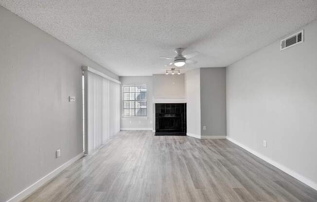 A spacious room with a fireplace and wood flooring.