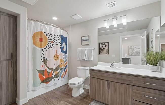 A bathroom with a toilet, sink, and a shower curtain with a floral pattern.