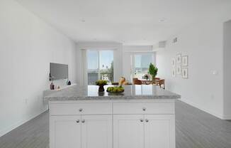 A kitchen with white cabinets and a marble countertop.