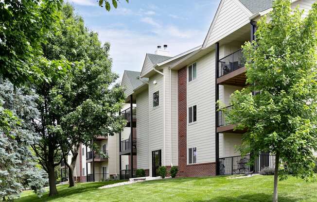 Apartment building with balconies and trees in front.