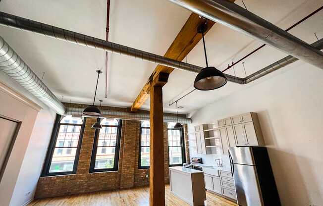 A kitchen with a refrigerator, cabinets, and a window.