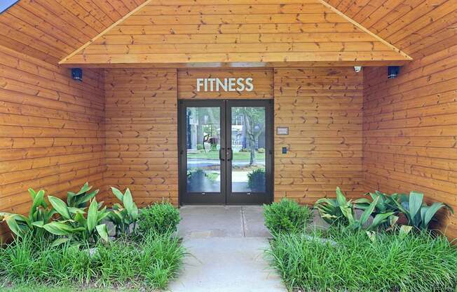 A fitness center entrance with a glass door and a sign above it.