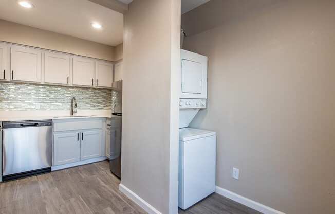 a kitchen with white cabinets and a white washer and dryer  at Sofia Apartments, Tempe