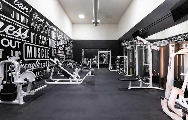a gym with weights and cardio equipment and a wall covered in graffiti
