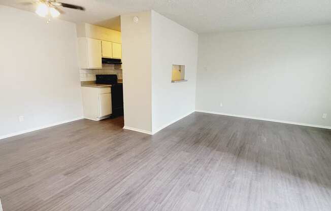 an empty living room with a wood floor and a ceiling fan