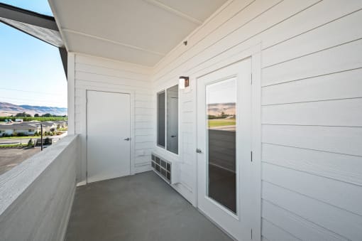 a view from the balcony of a white house with a door and a window at Gateway Apartments, East Wenatchee , WA 98802