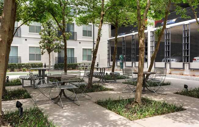 A patio with a table surrounded by chairs and trees.