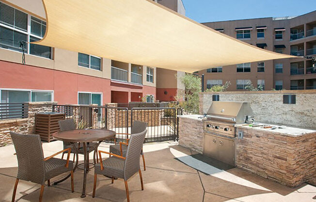 2-Bedroom Modern Apartments In San Rafael, CA - Rafael Town Center - BBQ Area With Viking BBQ Grill, Tables, And Chairs Under Shade.