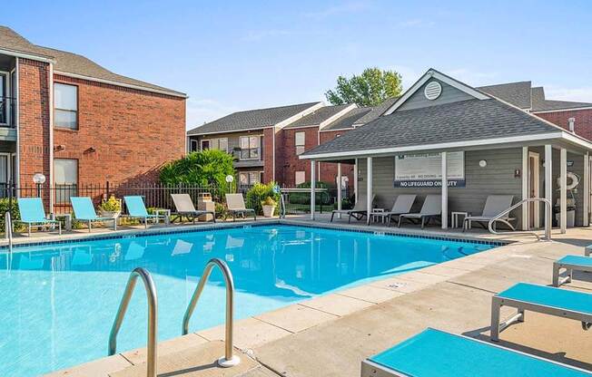 a swimming pool with tables and chairs in front of a building