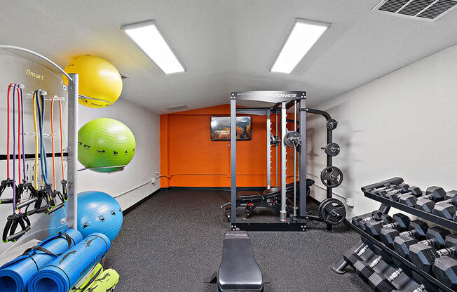 A gym with a variety of equipment including a bench, weights, and resistance bands.