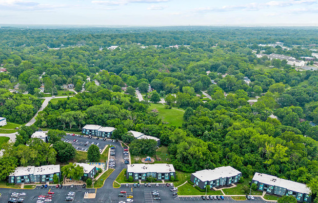 an aerial view of a parking lot with houses and trees