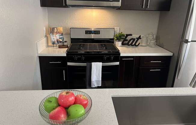 a kitchen with black cabinets and a bowl of apples