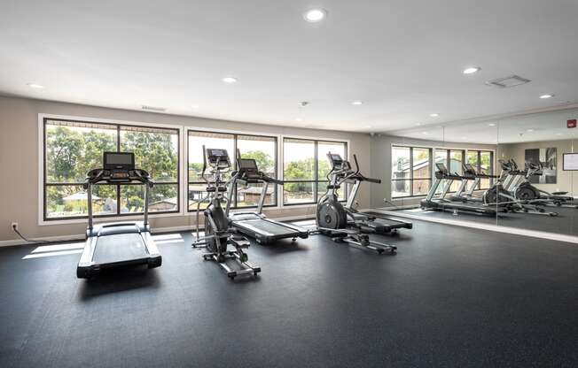 the gym has plenty of exercise equipment and windows