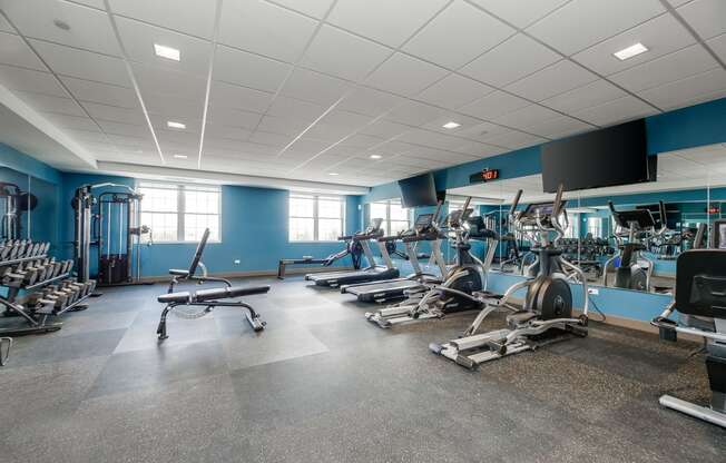 a gym with weights and cardio equipment in a building with blue walls