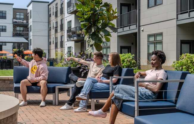 a group of people sitting on blue chairs in a courtyard