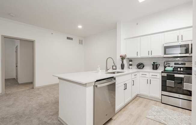 a white kitchen with an island and stainless steel appliances