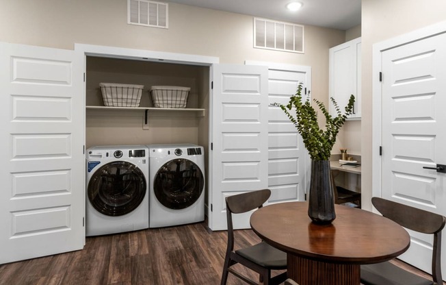 a washer and dryer in a laundry room with a table and chairs