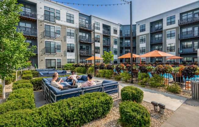 people sitting on a couch in an outdoor courtyard at an apartment building
