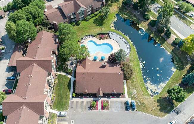 A bird's eye view of a residential area with houses, a swimming pool, and a river.