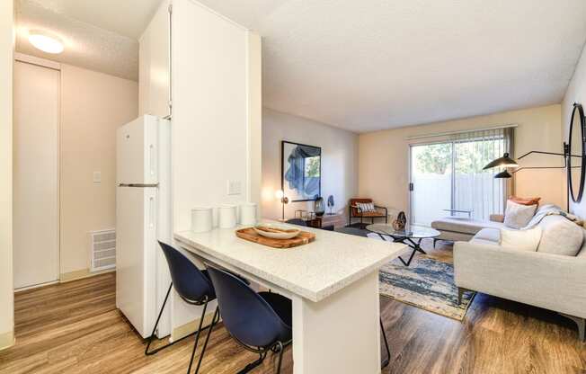 Kitchen with View of Living Room, Hardwood Inspired Floor, White Table and Blue Chairs at Renaissance Park Apartments, California, 95618