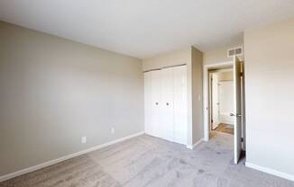 an empty bedroom with a closet and a door to a hallway