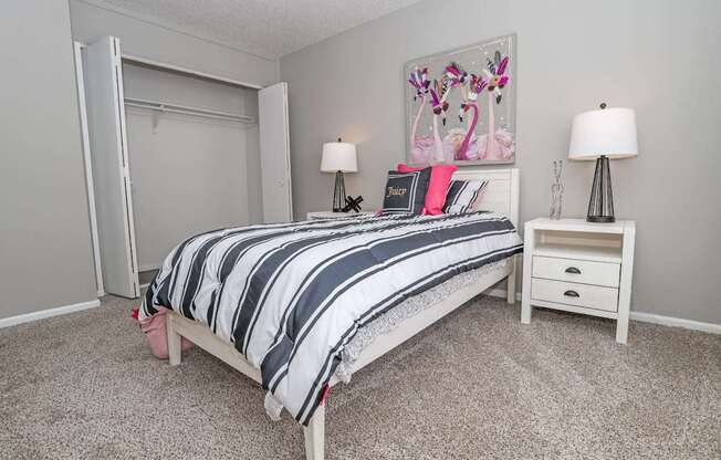 A bedroom with a bed, nightstands, and a painting of flamingos at Maplewood apartments in Shreveport, LA.