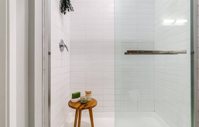 a white bathroom with a shower and a small wooden table