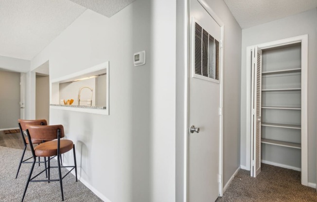 a hallway with a door to a closet and a table with a chair