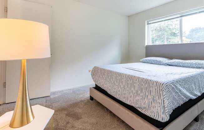 an empty bedroom with a bed and a lamp