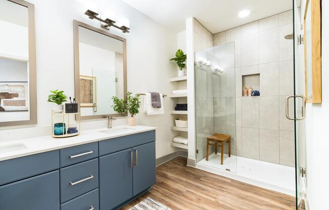 A refined primary bath with a glass-enclosed shower, open shelving, and clean-lined finishes that support a calm, everyday routine.