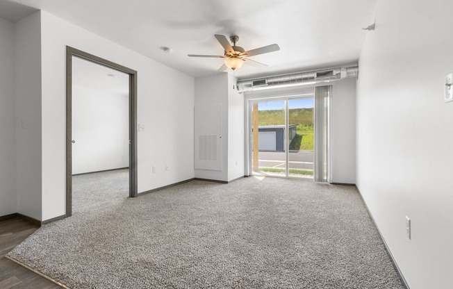 A room with a carpeted floor and a ceiling fan.