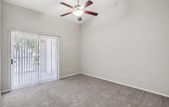 A room with a ceiling fan and a sliding glass door.