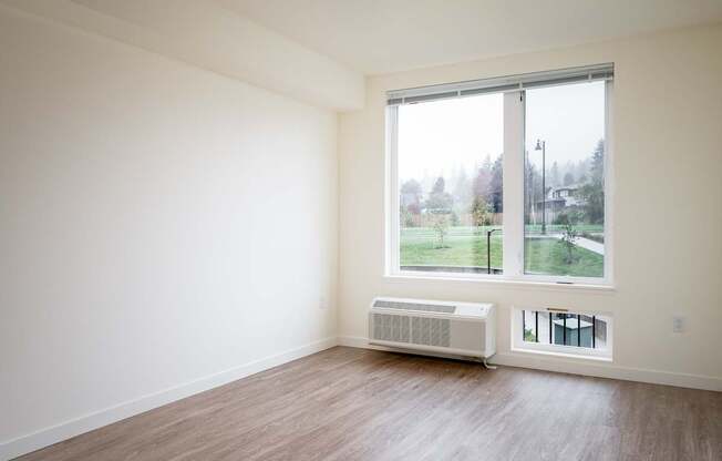 an empty room with a large window and wood floors