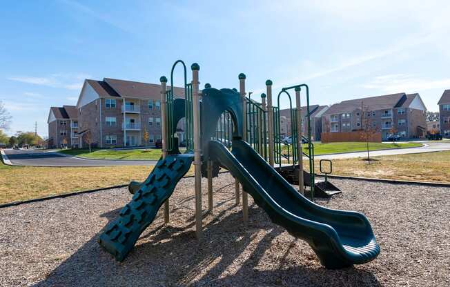 A green playground slide in a residential area.