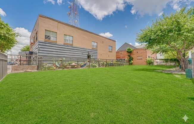 Spacious lawn area with community building at Vue Live Oak Apartments, Texas