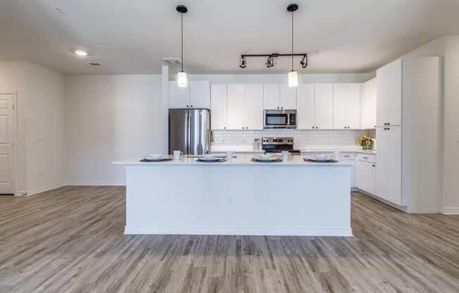 an open kitchen and living room with white cabinets and a large island